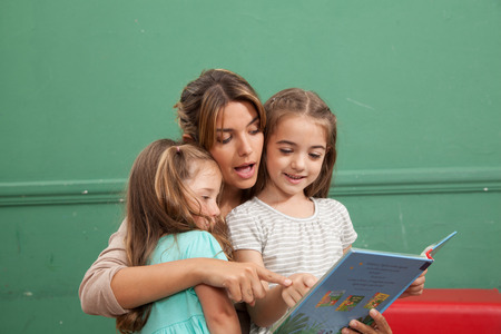 Young woman reading a book with her studentsの写真素材