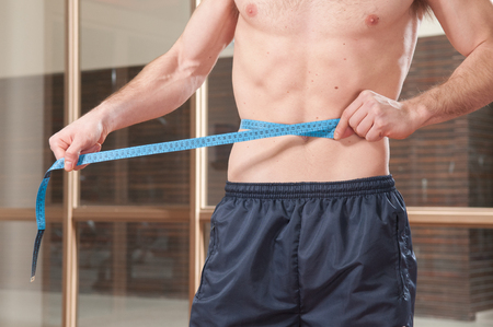 man measuring his waistの写真素材