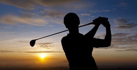 golfer silhouette during sunset with dramatic skyの写真素材