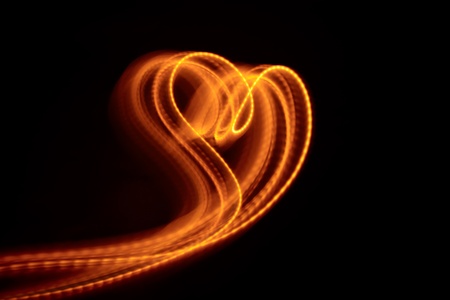 heart shape flowing light against black backgroundの写真素材