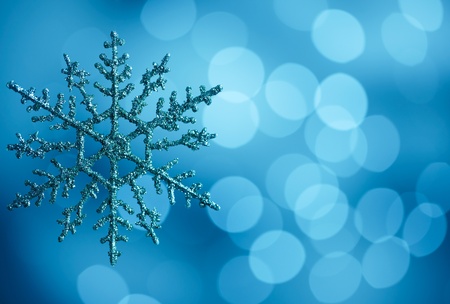 snowflake against blue bokeh lights background with copy spaceの写真素材