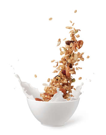bowl of granola with milk splashing isolated on whiteの写真素材