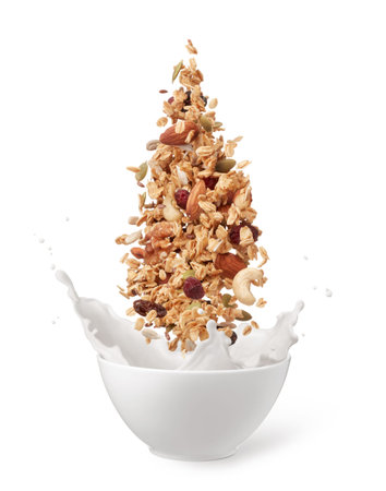 granola dropping into bowl of milk creating splash