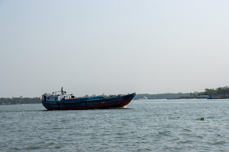 Troller boat on the river delivering goods close-up photo. Beautiful rural area and water vessel transportation. Beautiful sky and river horizon scenery with a motorboat. Restless river and blue sky.の写真素材