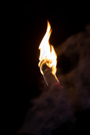 Fire torch on a dark background. A wooden torch with burning fire close-up shot. Torch with flame at night time. A wooden torch close-up view with bright yellow fire. Beautiful flame on a torch.の写真素材