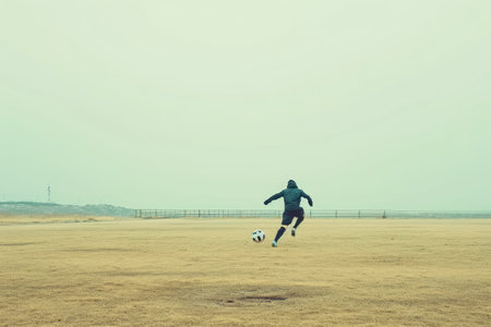 A skilled man kicks a soccer ball with precision and power as he traverses across a sprawling field, A soccer player practicing drills in an empty field, AI Generatedの素材