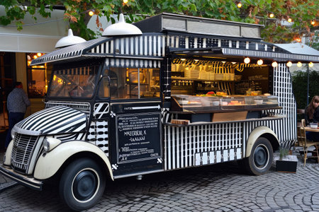 A food truck is parked on a cobblestone street, serving delicious meals to hungry customers, Food truck decorated in vintage Parisian style, AI Generatedの素材