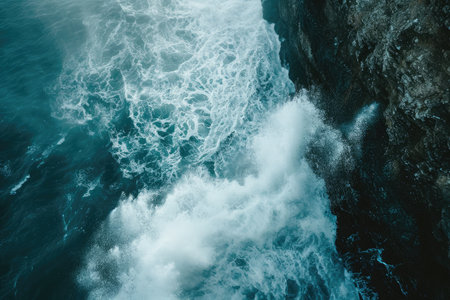 A powerful body of water crashes against a towering rocky cliff, creating an awe-inspiring spectacle, Waves breaking against an ocean cliff, causing a spray, AI Generatedの素材