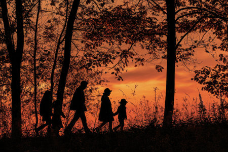 A group of individuals walking through a forest during the setting sun, surrounded by trees and nature, Silhouette of a family going for a Thanksgiving Day walk in the woods, AI Generatedの素材