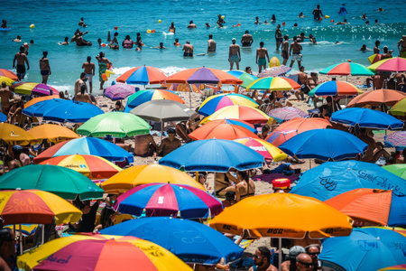 Large group of people gathered on the beach, relaxing under colorful umbrellas on a sunny day, A crowded beach dotted with colorful umbrellas and sunbathersの素材