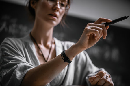 Close-up of a teacher writing with a marker during a class session that focuses on real-life applications of the subject matter in a classroom environmentの素材
