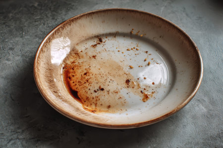 Dirty dishes with sauce smeared on plate resting on a countertop in a kitchen setting after a mealの素材