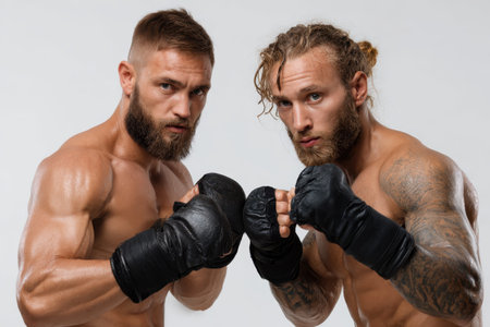 Two professional martial artists showcasing their strength and readiness in an intense training portraitの素材