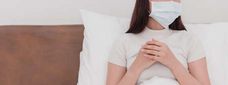 Asian woman wearing mask, sick doctor, cough, use to grasp the chest in the bedroomの写真素材
