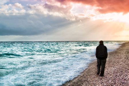 Shilouette of a man walking on the beach at sunset in Greece.の写真素材