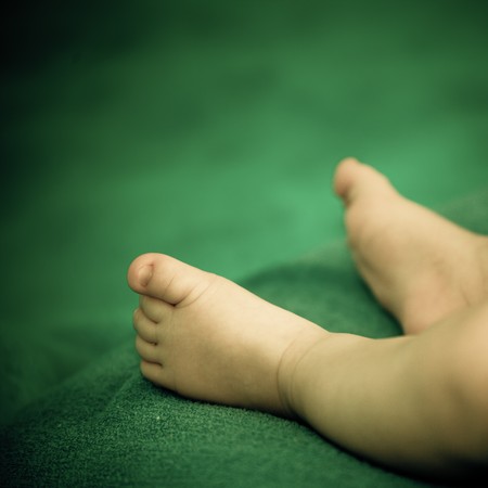 Small feet of a new baby born on a green backgroundの写真素材