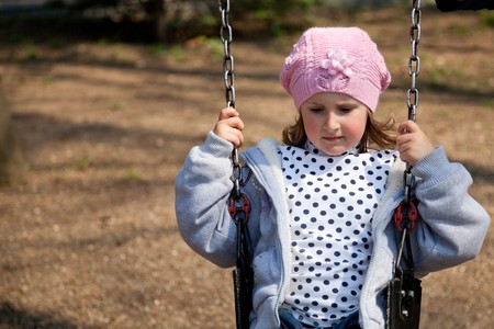 Little girl enjoying the swing in a spring day in the park.の写真素材