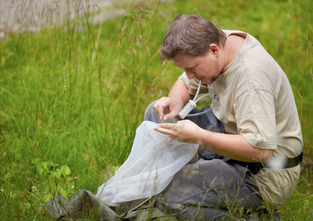 Entomologist collecting bugs from the net with an entomological aspirator in summer.