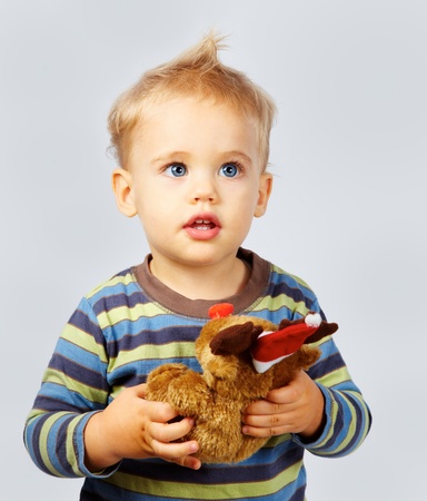 Studio portrait of a one year old baby boy on gray with Christmas toy in hand.の写真素材