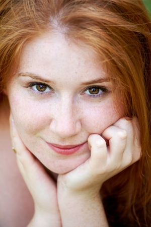 Portrait of a beautiful 20 year old redhead woman looking at camera and smiling.の写真素材