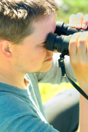Caucasian young man looking at birds through a binocular.の写真素材