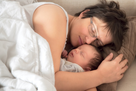 Mommy and her newborn baby boy asleep hugging.の写真素材