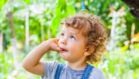 Portrait of 1 year old baby boy sucking his finger outdoor.の写真素材