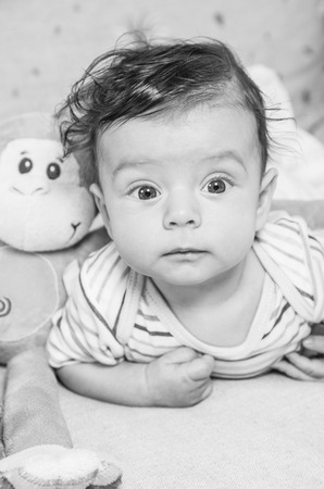 Portrait of an adorable smiling baby playing with a monkey toy.の写真素材