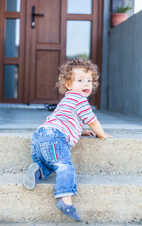 Portrait of 1 year old baby boy climbing down the stairs.の写真素材
