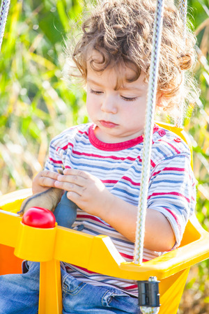 Portrait of 1 year old baby boy playing in a swing.の写真素材