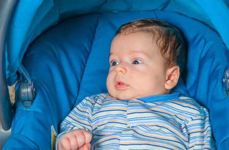Portrait of a 2 months old baby boy sitting in a safety seat.