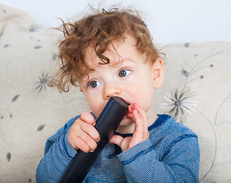 11 months old baby boy studing the tv remote control.の写真素材