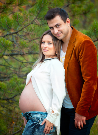 Pregnant woman with her husband relaxing outdoor.の写真素材