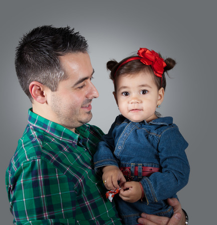 18 months old baby girl in her daddy's arms, studio shot.の写真素材