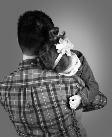 18 months old baby girl in her daddy's arms, studio shot.の写真素材