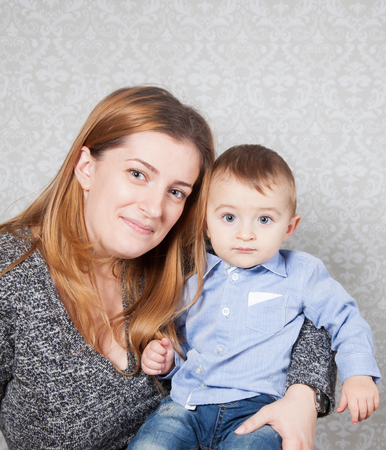1 year old baby boy in his mother's arms, studio portrait.の写真素材