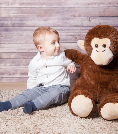 Baby boy portrait with a huge stuffed brown monkey toy.の写真素材