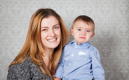 1 year old baby boy in his mother's arms, studio portrait.の写真素材