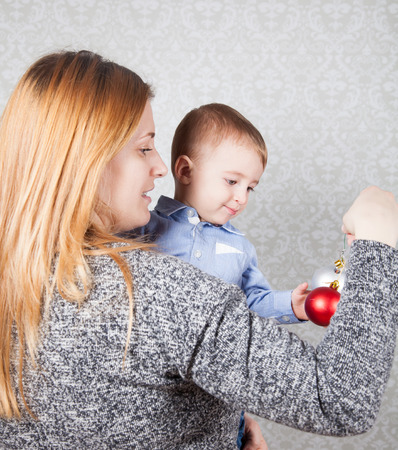 1 year old baby boy in his mother's arms, studio portrait.の写真素材