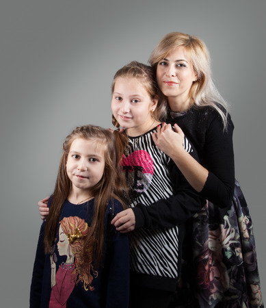 Portrait of a beautiful mother with her 2 daughters, studio shot.の写真素材