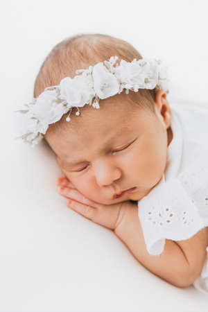 Newborn baby girl portrait, photographed in studio. Dressed in white dress.の写真素材