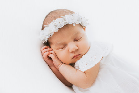 Newborn baby girl portrait, photographed in studio. Dressed in white dress.の写真素材