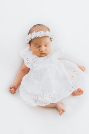Newborn baby girl portrait, photographed in studio. Dressed in white dress.の写真素材