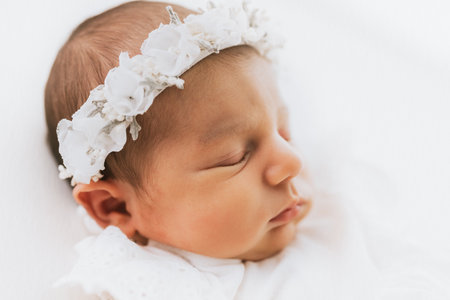 Newborn baby girl portrait, photographed in studio. Dressed in white dress.の写真素材
