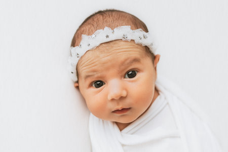 Newborn baby girl with opened eyes, looking at the camera.の写真素材