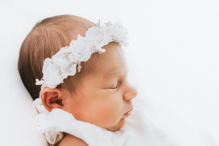Newborn baby girl portrait, photographed in studio. Dressed in white dress.の写真素材