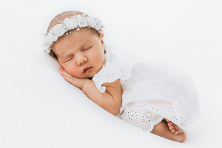 Newborn baby girl portrait, photographed in studio. Dressed in white dress.の写真素材