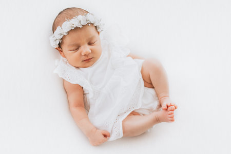 Newborn baby girl portrait, photographed in studio. Dressed in white dress.の写真素材