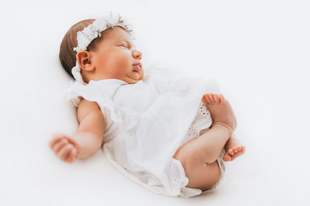 Newborn baby girl portrait, photographed in studio. Dressed in white dress.の写真素材