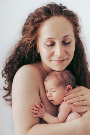 Portrait of mother holding her baby, photographed in studio, on white background.の写真素材